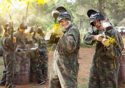 Two cheerful paintball players in full gear having fun outdoors