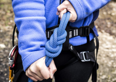 female hands holding a climbing rope with a secure node